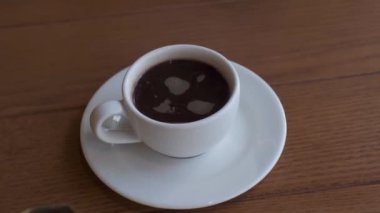 Kahve dükkanındaki masada beyaz bir fincan ve çay tabağı var. Kahveli bir Türk. Yavaş Hareket, Kapat.