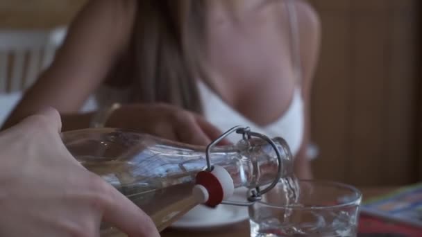 Una Giovane Donna Vestita Bianco Chiaro Versa Acqua Bicchiere Mentre — Video Stock