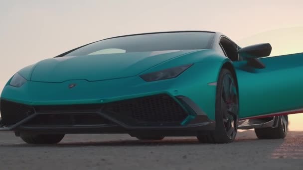 アラブ首長国連邦 ドバイ 2023 開いたドアを持つ高価なスポーツカーは 砂漠の真ん中にある道路上の夕日を背景に立っています スローモーション — ストック動画