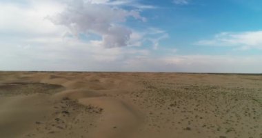 Hava aracı bulutlu bir günde kumlu bir çöle iniyor. Hava görünümü