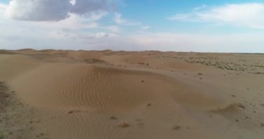 Dronn bulutlu bir günde çölün kum tepelerinin üzerinden uçar. Hava görünümü