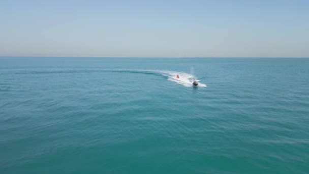 アラブ首長国連邦 ドバイ 2023 ドローンは 人々と膨脹可能なボートを引っ張るジェットスキーの上に飛ぶ エアリアルビュー スローモーション — ストック動画