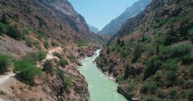 İnsansız hava aracı bulutsuz bir günde nehirde uçuyor. Etrafı dağlarla çevrili. Hava Görünümü, Yavaş Hareket.