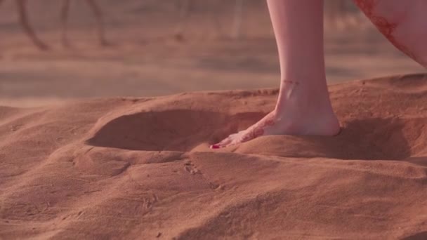一个穿着蓝色长裙 头发飘扬的年轻女子赤脚走过沙漠沙丘 旁边是一个被沙子覆盖的城市 慢动作 — 图库视频影像