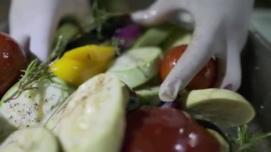 Beyaz eldivenli bir aşçı elleriyle bir konteynırda kesilmiş sebzeleri karıştırır. Yavaş Hareket, Kapat.