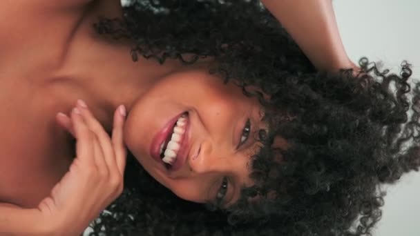 アフロ様式および明るい構造のカーリー ヘアーが付いている若い笑顔モデルの縦の肖像画 スローモーション クローズアップ — ストック動画
