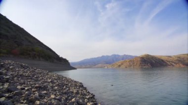 Bulutlu bir günde kayalarla çevrili derin bir dağ gölü. Yavaş çekim