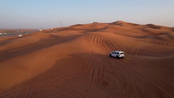 無人機は砂漠の砂丘を通って白いSuvの運転の上を飛ぶ 空中スローモーション — ストック動画