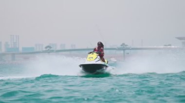 Açık denizlerde jet ski üzerinde can yeleği giymiş esmer bir kadın. Yavaş çekim