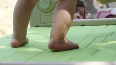 Çocuk bahçesinde çıplak ayakla yürüyen küçük bir çocuğun bacakları. Kapat, Yavaş Hareket.