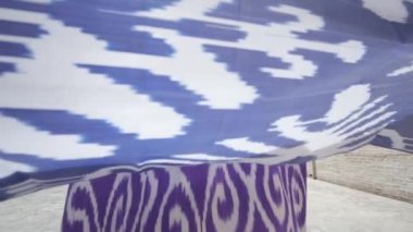 Uzun saçlı, doğulu cüppeli ve kafatası şapkalı genç bir kadın antik bir doğu şehrinde yürüyor. Yavaş Hareket, Özbekistan