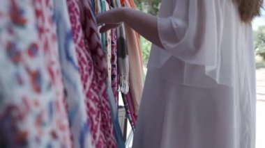 Uzun saçlı, açık renk elbiseli genç bir kadın parlak doğulu kumaşlar seçiyor. Yavaş Hareket, Özbekistan