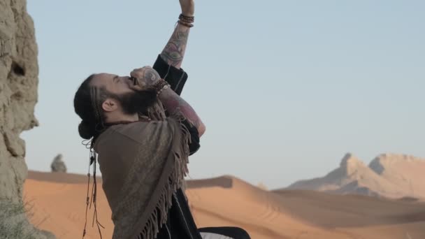 Man Dressed Shaman Standing Rock Middle Desert Sands Playing Harmonica — Stock Video