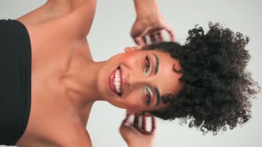 Siyah kıvırcık saçlı ve parlak makyajlı esmer bir kadının portresi. Gülümsüyor ve gülüyor. Kapat, Yavaş Hareket