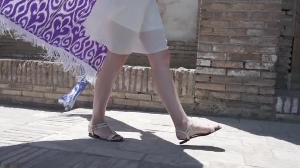 東洋の衣を着た長髪の若い女性とスカルキャップは 古代の東洋の都市を歩く スローモーション ウズベキスタン — ストック動画