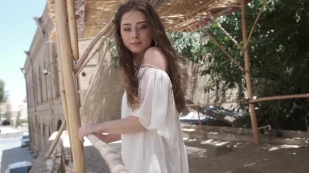 一位头发飘扬的年轻女子穿着白色的太阳衣 在芦苇树冠下走过一座古城 乌兹别克斯坦慢动作 — 图库视频影像
