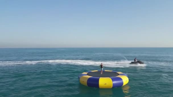 アラブ首長国連邦 ドバイ 2023 ドローンは 背後にあるドバイとヨットの周りの海上にジェットスキーに乗っている人々と電気ホイルボードを飛ぶ エアリアルビュー スローモーション — ストック動画