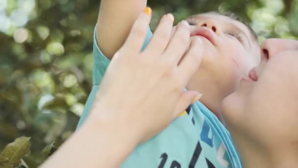 Egy Kisfiú Anyja Karjaiban Próbál Zöld Almát Szedni Egy Faágból — Stock videók