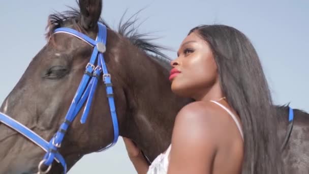一个身穿白色比基尼的年轻的黑衣女子站在海滨的一匹马旁边 慢动作 — 图库视频影像
