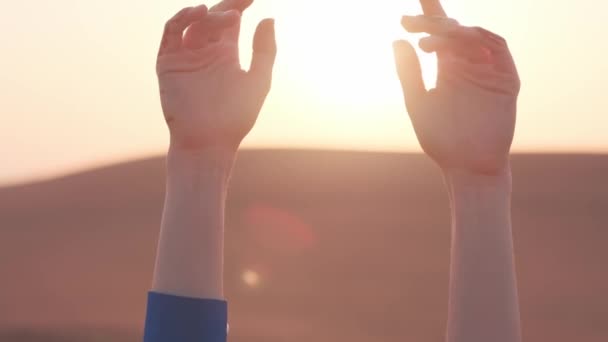 砂漠の砂の上の長い青いドレスに立っている若い女性の手は 設定された太陽の背景に対して スローモーション クローズアップ — ストック動画