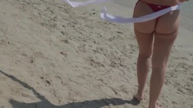 Kırmızı bikinili, kısa beyaz gömlekli, kumlu sahilde yalınayak duran genç, seksi esmer kadın. Yavaş Hareket