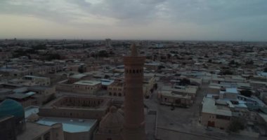 Şafak vakti Buhara 'daki ünlü Kalyan Poi Kalon Kompleksi ve Poi Kalon Minaret, Poi Kalan veya Po-i-Kalyan anıtında bir İHA uçar. Hava manzarası, Özbekistan
