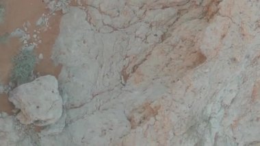 Çöldeki kumların tepesinde duran kırmızı elbiseli genç bir kadının yanından bir dron uçuyor. Hava görünümü
