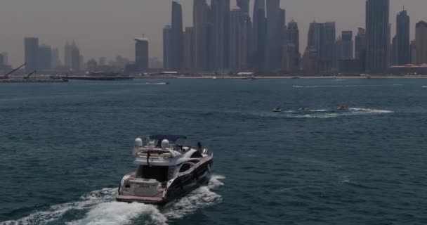 無人機がプライベートボートで街に向かって穏やかな海を航行します 空中ビュー スローモーション ドバイ — ストック動画