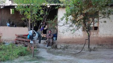 Tashent, Özbekistan - 411 2022: Asyalı bir adam evinin yanında bir ağacın yanında. Yavaş Hareket.