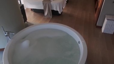 İki yataklı, su ve köpükle dolu bir küveti olan pahalı bir otelde masaj odası. Yavaş çekim