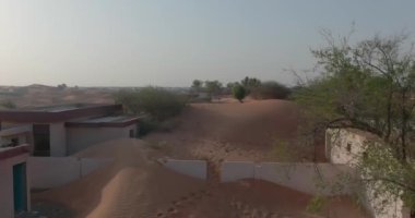 Bir dron Dubai çölünün ortasında kumla kaplı küçük bir kasabada bir deve kervanı yakalıyor. Hava, Yavaş Hareket.
