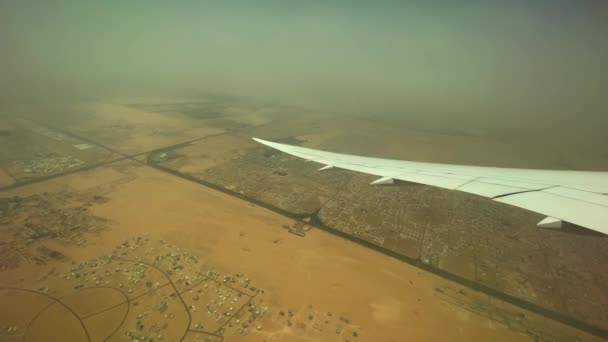 翼の上の飛行機からのビデオ その下のドバイの土地と地平線上の塵嵐 空中風景 — ストック動画