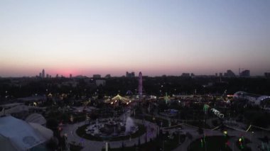 Bir dron lunaparkın üzerinde atlı karınca ve dönme dolap ile uçuyor. Gece, hava manzaralı.