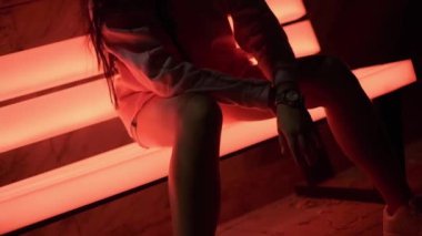 Gece parkında parlayan bankta oturan spor kıyafetli genç bir kadın. Yavaş Hareket