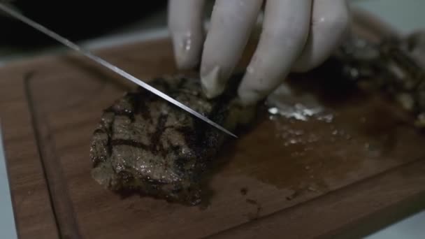 シェフはナイフでまな板の上で肉料理をカットします スローモーション クローズアップ — ストック動画