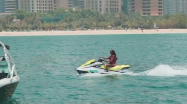 Açık denizlerde jet ski üzerinde can yeleği giymiş esmer bir kadın. Yavaş çekim