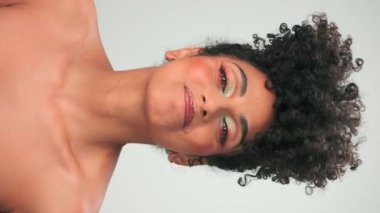 Siyah kıvırcık saçlı ve parlak makyajlı esmer bir kadının portresi. Gülümsüyor ve gülüyor. Kapat, Yavaş Hareket