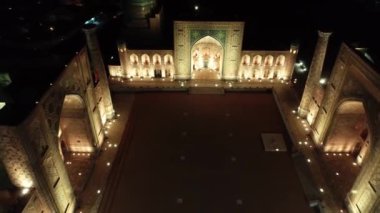 Aydınlanmış Registan kompleksinin insansız hava aracı panoraması, Semerkant, Özbekistan. Hava Görünümü, Yavaş Hareket.