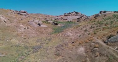 İnsansız hava aracı bulutsuz bir günde dağlarla çevrili kayalık tepelerin üzerinden uçar. Hava Görünümü, Yavaş Hareket