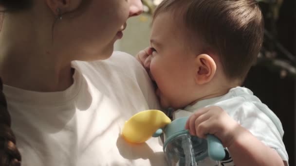 Malý Chlapec Náručí Mladé Matky Drží Plastový Kelímek Vodou Zavřít — Stock video
