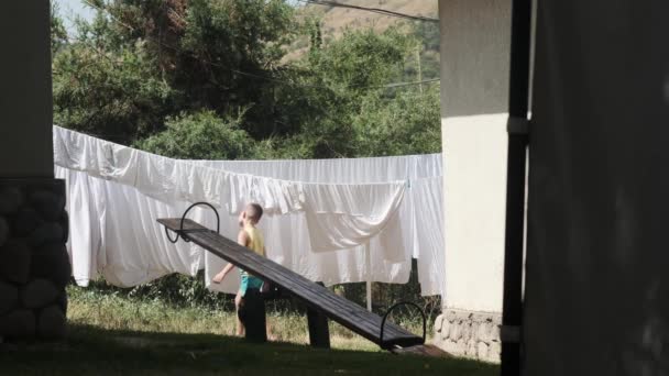 Seorang Remaja Berjalan Sekitar Halaman Rumah Sebelah Tempat Tidur Linen — Stok Video