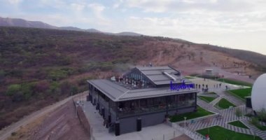 İnsansız uçak, yanındaki restoranla birlikte teleferiğin dağ istasyonunun etrafında uçuyor. Günbatımı gökyüzünün arka planında. Hava görünümü