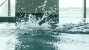 Küçük bir oğlu olan genç bir atletik adam pahalı bir otelin havuzunda yüzüyor. Yavaş Hareket.