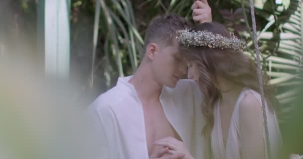 Young Couple Lovers Light White Robes Swing Blooming Spring Garden — Vídeo de stock