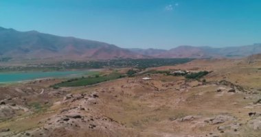 İnsansız hava aracı, bir dağ gölünün kıyısındaki küçük bir kasaba da dahil olmak üzere tepelerin üzerinden uçuyor. Hava Görünümü, Yavaş Hareket