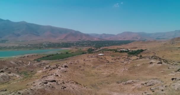 Dron Vuela Sobre Las Colinas Incluyendo Pequeño Pueblo Orillas Lago — Vídeo de stock