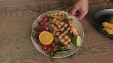 Şef kızarmış balık, otlar, sebzeler ve limonla servis edilen bir tabak gösteriyor. Yavaş Hareket, Kapat.