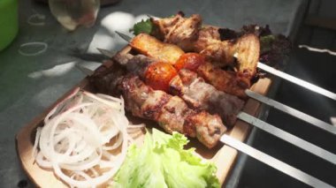 Şef ahşap bir tahtanın üzerinde tavuk, pelerin ve ciğer ile kebap, soğan, bitki, domates ve sebze servis ediyor. Yavaş Hareket, Kapat.