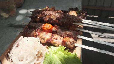 Bir garson ahşap tepsiyi tavuk, et ve ciğer kebabıyla gösteriyor, soğan, bitki ve sebzelerle servis ediliyor. Yavaş Hareket, Kapat.