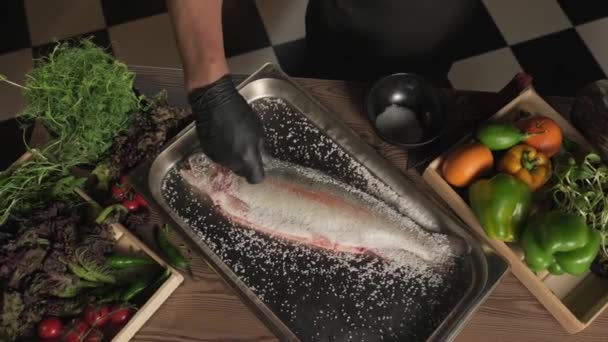 Chef Handskar Saltning Och Peppering Fisk Som Ligger Köksbord Omgiven — Stockvideo